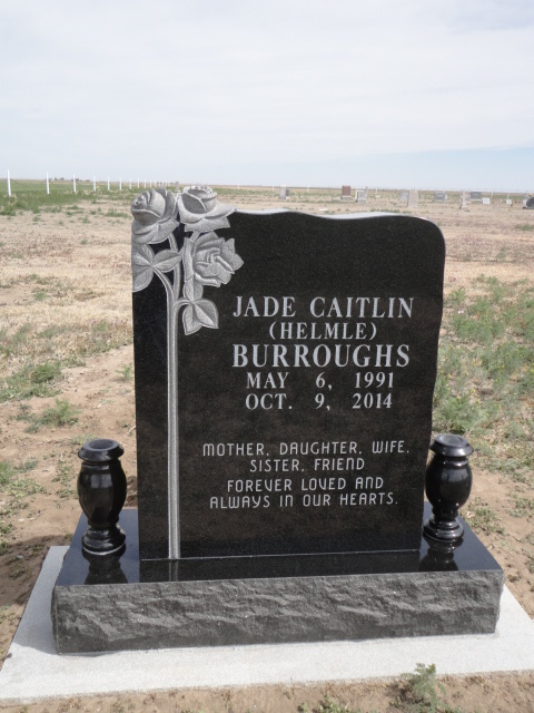 A black headstone with three flower designs